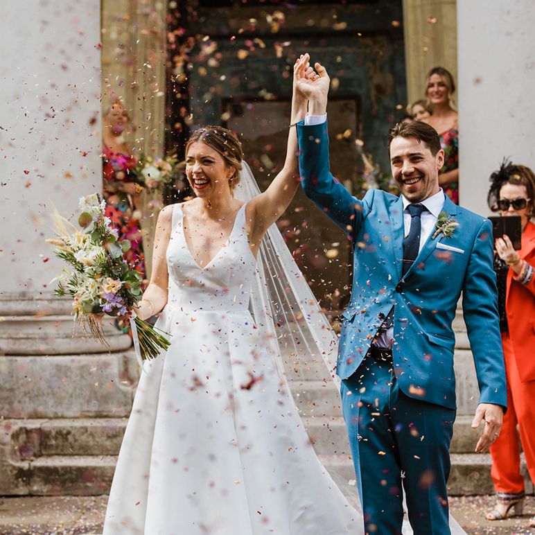 Bride and groom walk out into their confetti exit at industrial city wedding 