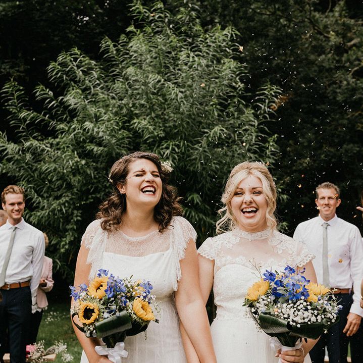 Yellow, purple and white bouquets for brides having their confetti exit from ceremony