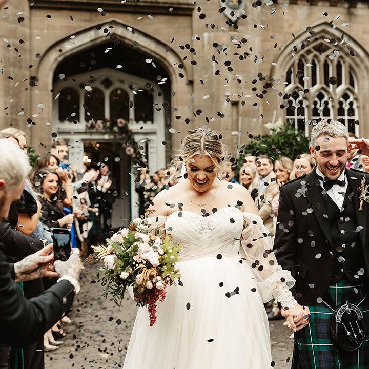 Bride and groom walk past all their wedding guests as they throw black confetti for the couple outside Drumtochty Castle 