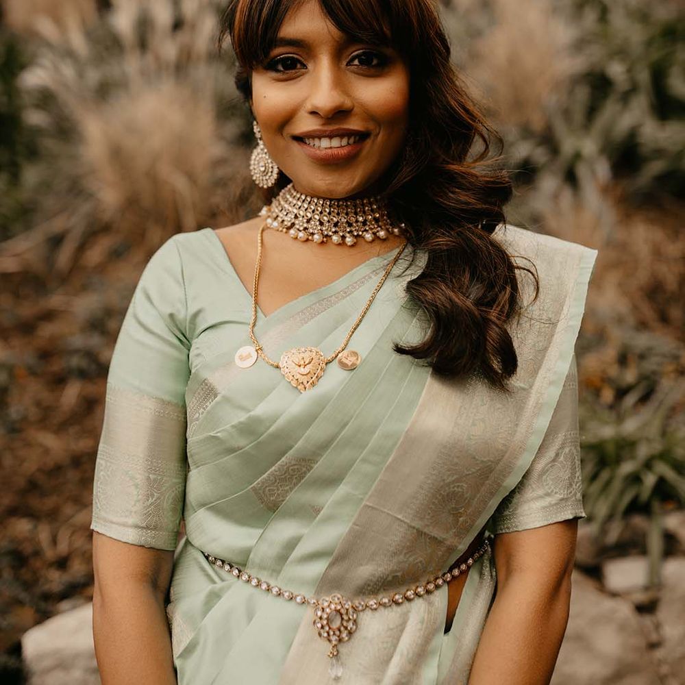 Bride in mint green saree with golden and pearl detailed jewellery and golden embellishments 