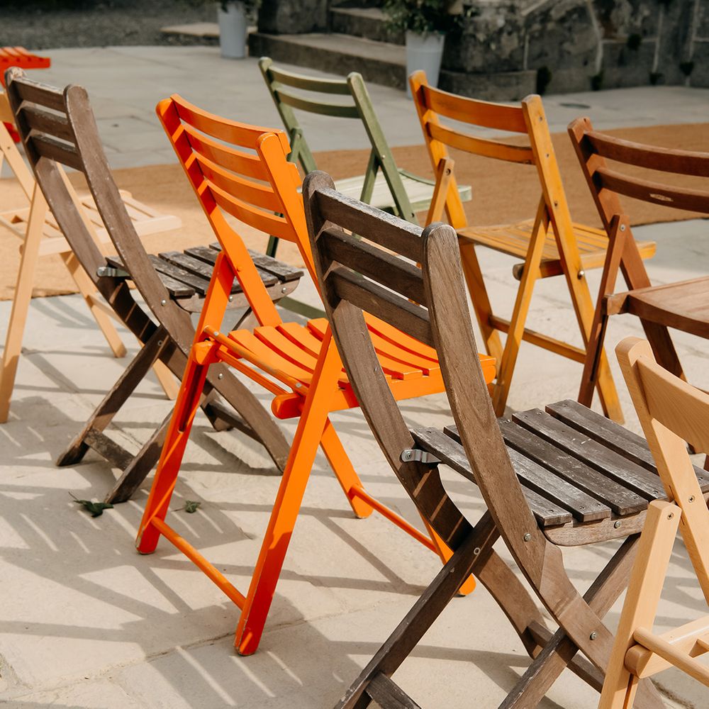 Colourful orange, yellow, green and brown fold chairs for wedding guests 