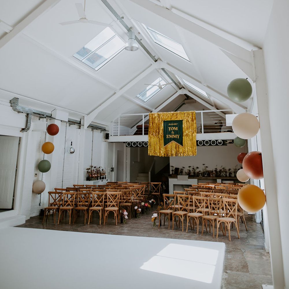 Gold streamers hang from ceiling complete with velvet banner and balloons for industrial styled retro wedding