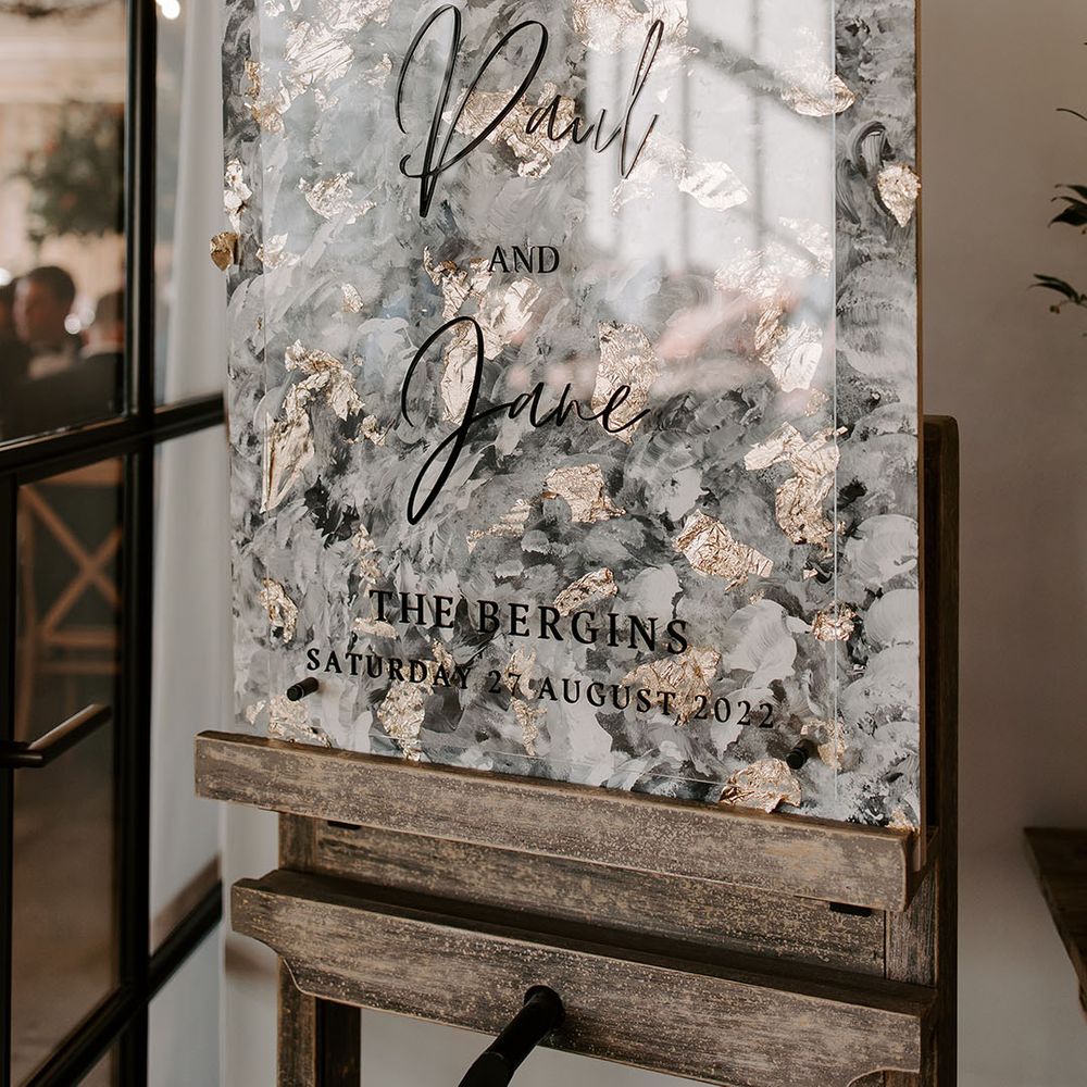 Perspex wedding sign in front of modern styled painted backdrop on wooden easel 