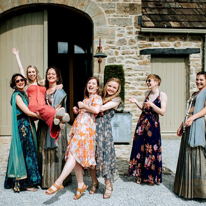 Wedding guests in colourful outfits outdoors at barn wedding 