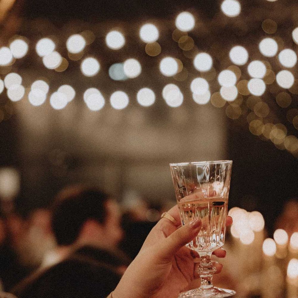 Wedding guest lifts glass during reception 