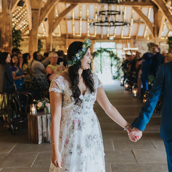 Indian bride in a Savin London Amelia dress and groom a blue suit descending up the aisle as husband and wife 