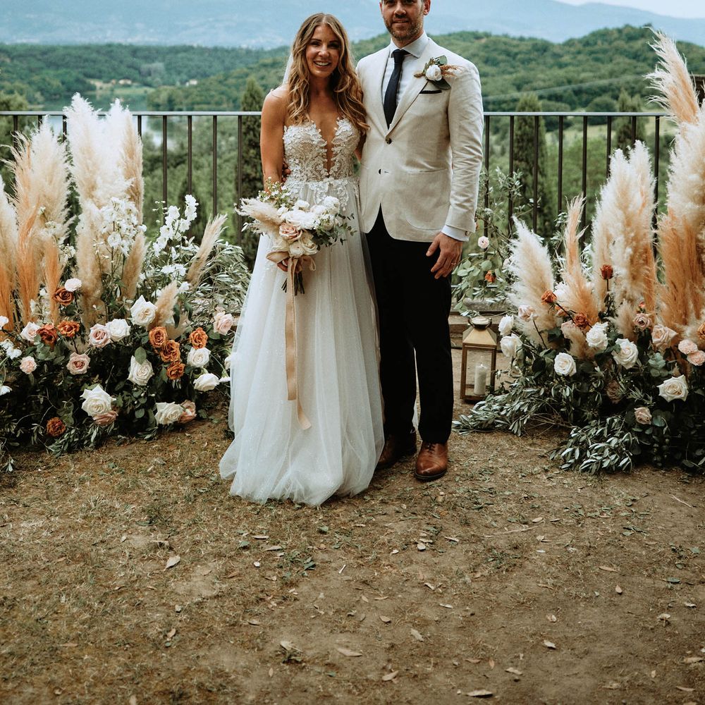 Bride and groom at altar with pampas grass, eucalyptus and white, orange and pink rose decor.