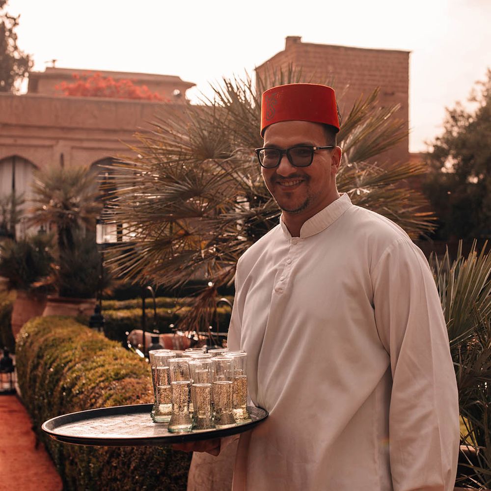 Wedding server in fez hat holding tray of wedding drinks 