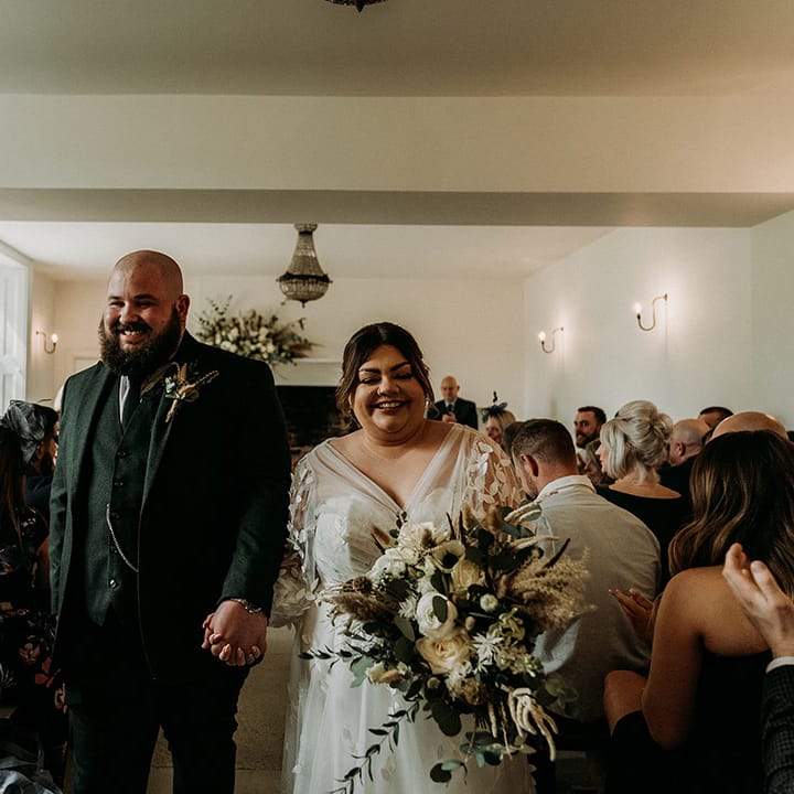 Groom in green tweed wedding suit walking back down the aisle with the bride as a married couple 