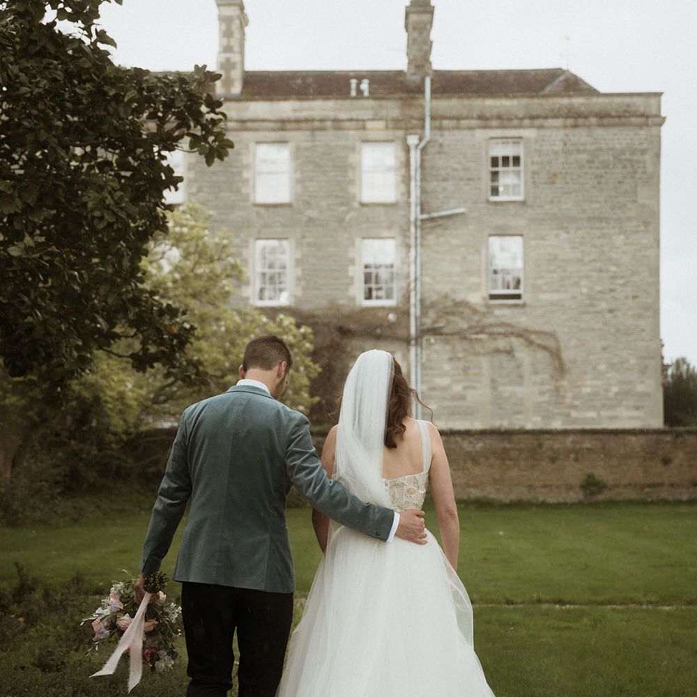 Bride in layered tulle wedding dress walking along with the groom at country house wedding 