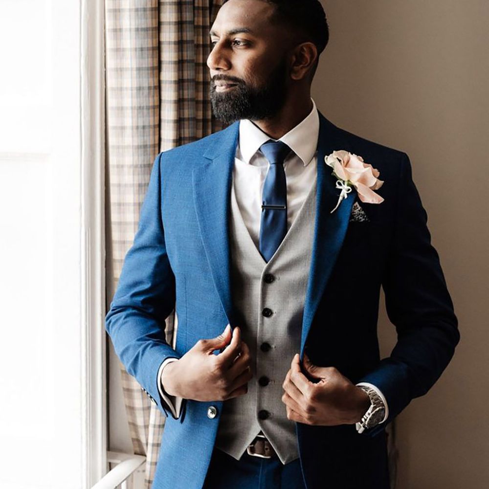 English Sri Lankan wedding with the groom wearing a dark navy wedding suit with grey waistcoat and pink buttonhole 