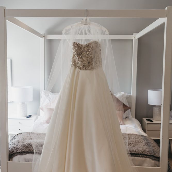 Oleg Cassini wedding dress and veil hanging up on the white four poster bed frame