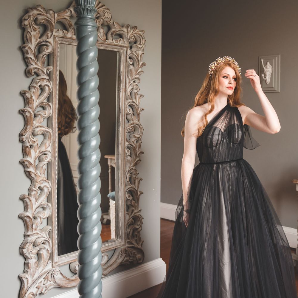Bride on the wedding morning in a one shoulder black tulle wedding dress with long auburn hair and wire hair accessory 
