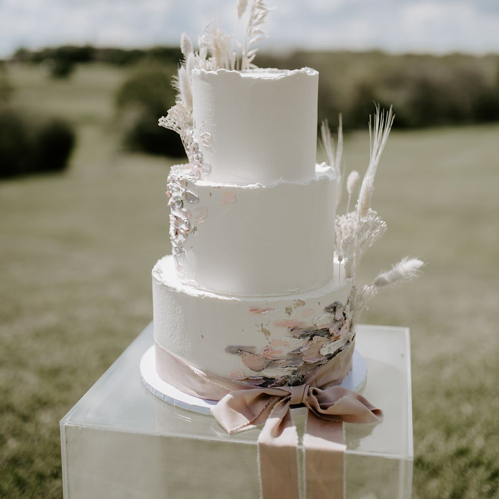 Three tier buttercream wedding cake with ribbon and dried flower decor