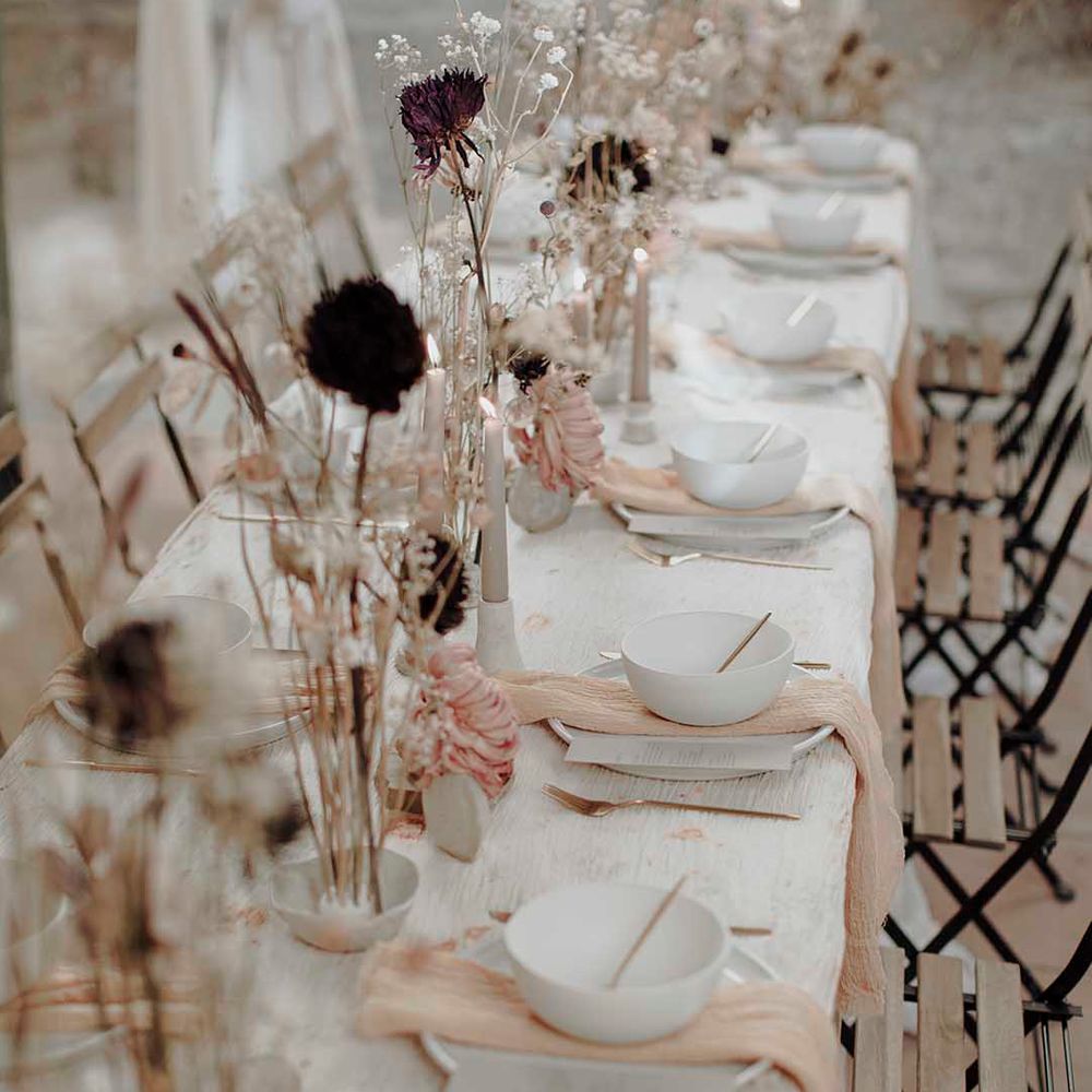 Minimalist wedding table decor with dried flower stems in ceramic vases, candles and natural linens 