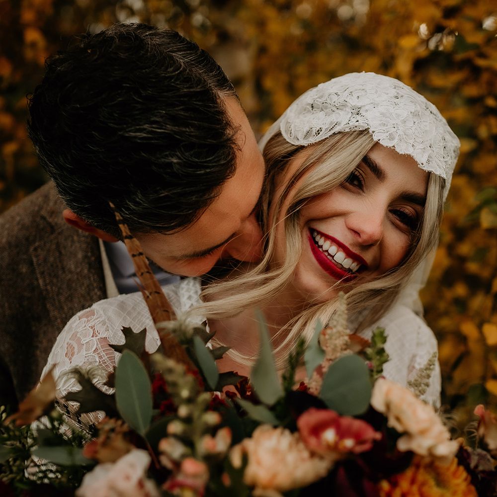Groom kissing his brides neck with bright red lipstick and lace Juliet cap veil 