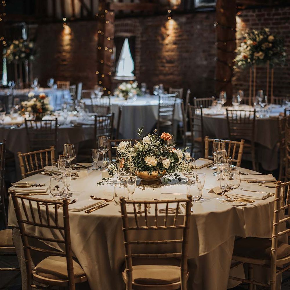 Tablescape with gold cutlery and gold rimmed glasses with orange and white flower arrangement in golden vase 