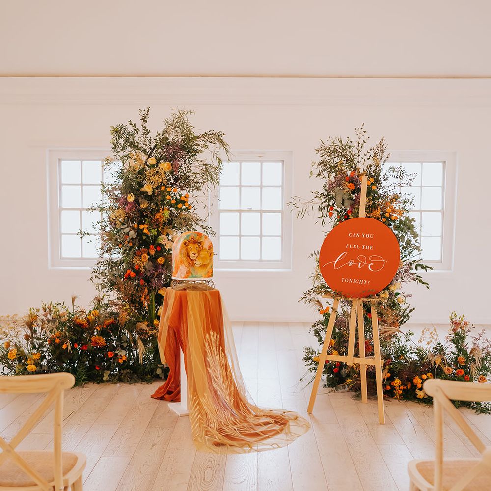Golden wedding inspiration with green and orange wedding flowers, orange circle wedding sign on an easel and a lion wedding cake 