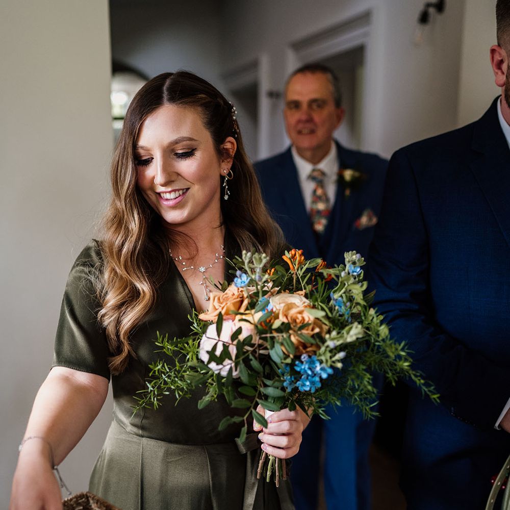 Bridesmaid in olive green dress and dainty matching earrings and necklace picks up some confetti 