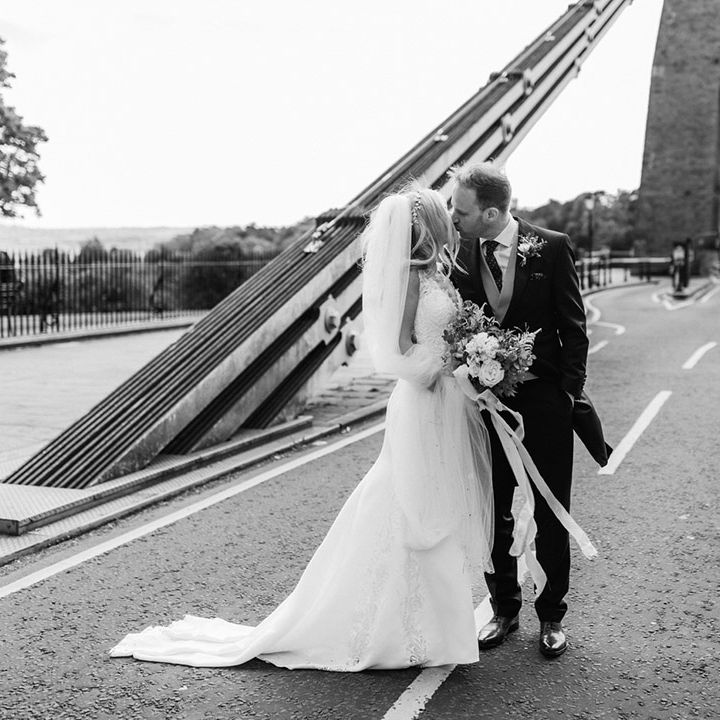 Bride and groom share a kiss standing on the Clifton suspension bridge in Bristol 
