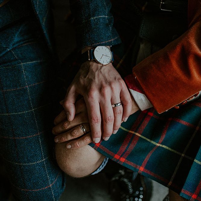Groom places his hand across grooms hand wearing tartan kilt 
