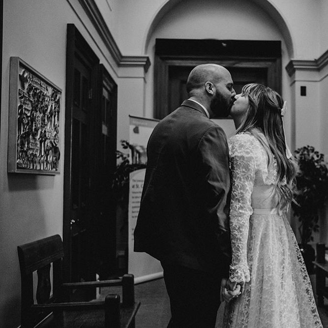 Bride wearing lace wedding dress kisses her groom after wedding ceremony at St. George's Hall, Liverpool 