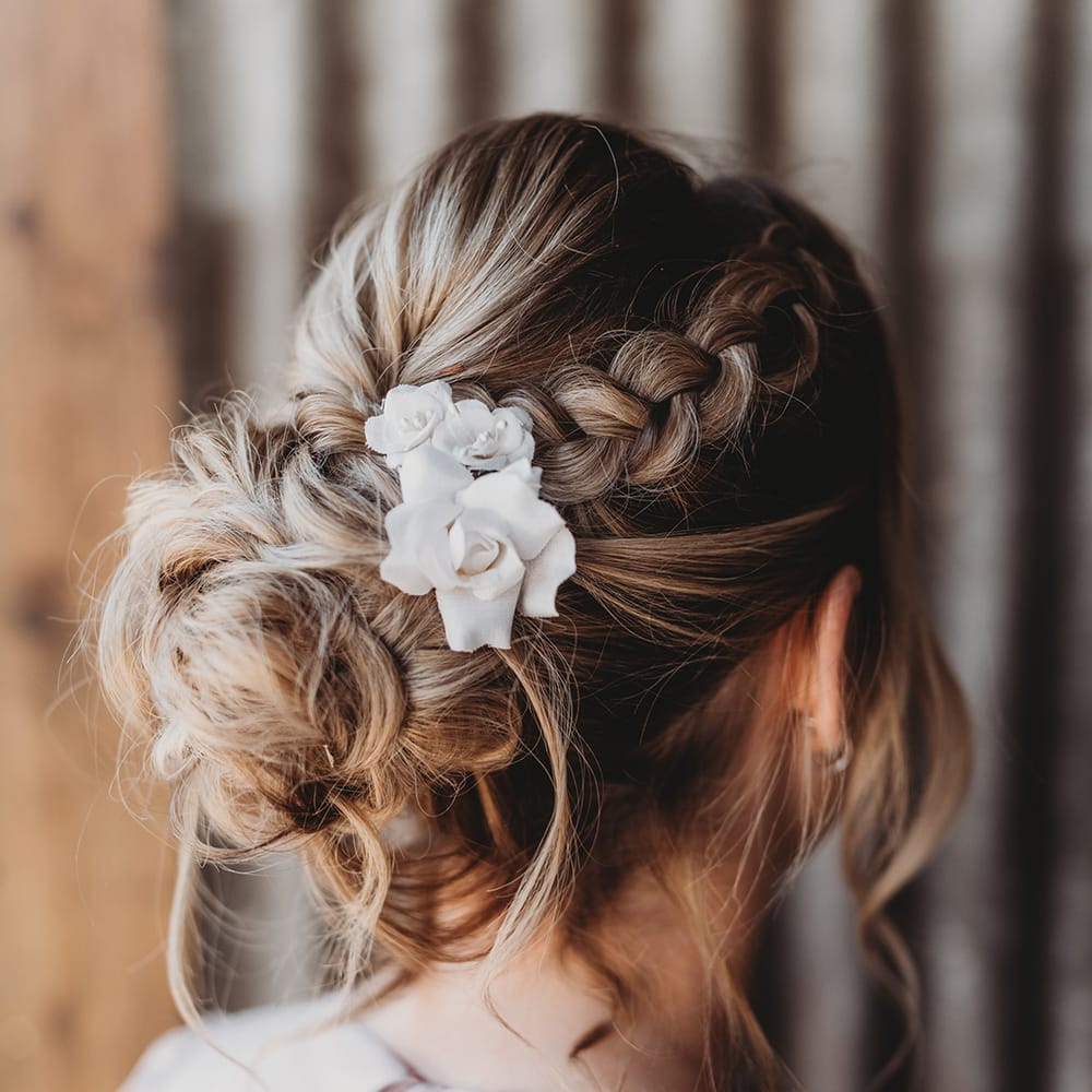 Bridesmaid with a braid going into a bun with a white flower hair accessory 