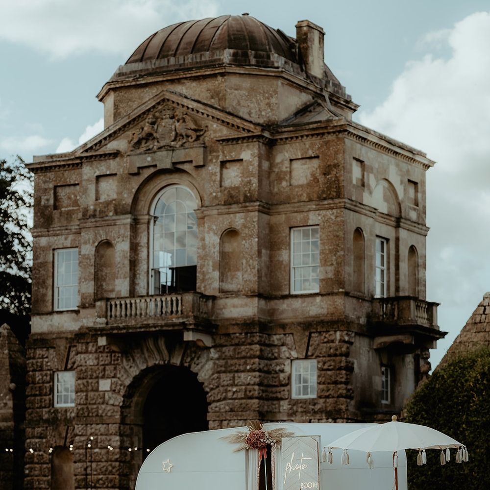 Caravan wedding Photo Booth with a neon sign. chalk board and tassel umbrella outside of the Badminton Estate 