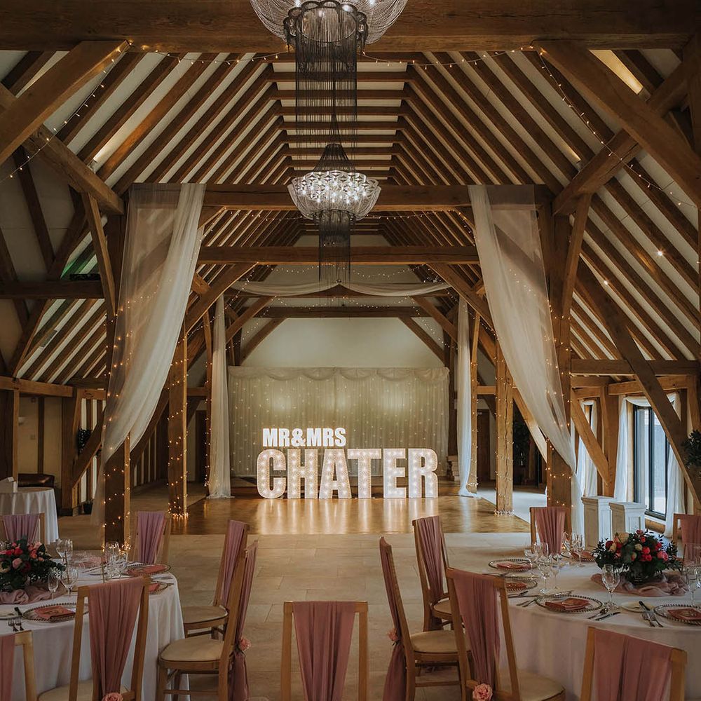 The Old Kent Barn wedding venue with drapes, fairy lights and light letters spelling out the couple's name 
