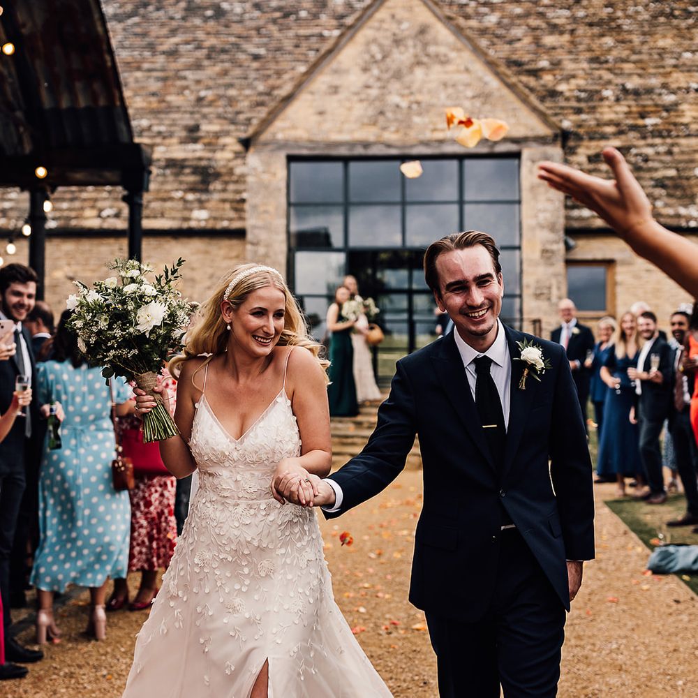 Bride in an Alexandra Grecco Lana dress having a confetti exit with the groom in a navy blue suit 