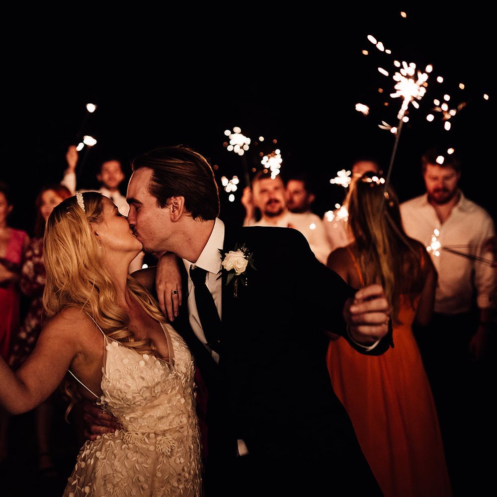 Bride and groom share a kiss during their sparkler send off 