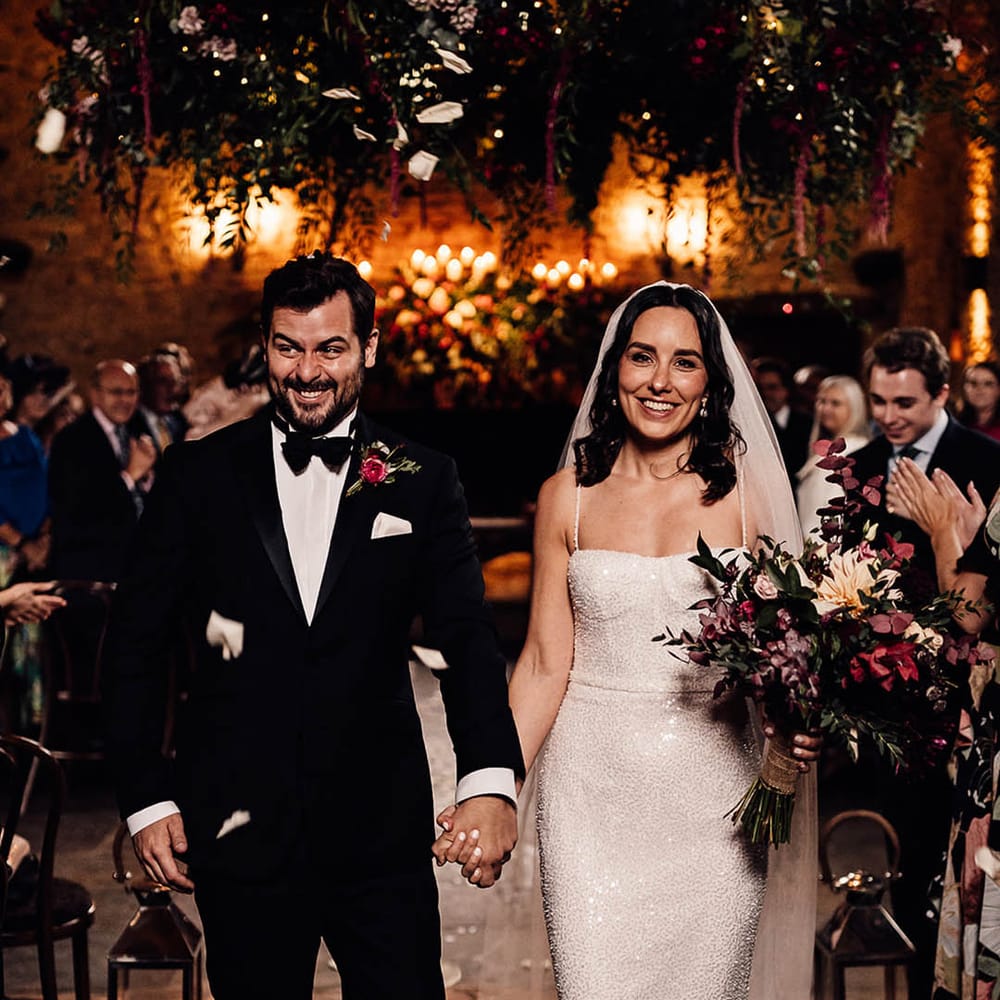 The wedding guests clap as the bride and groom exit the ceremony as a married couple