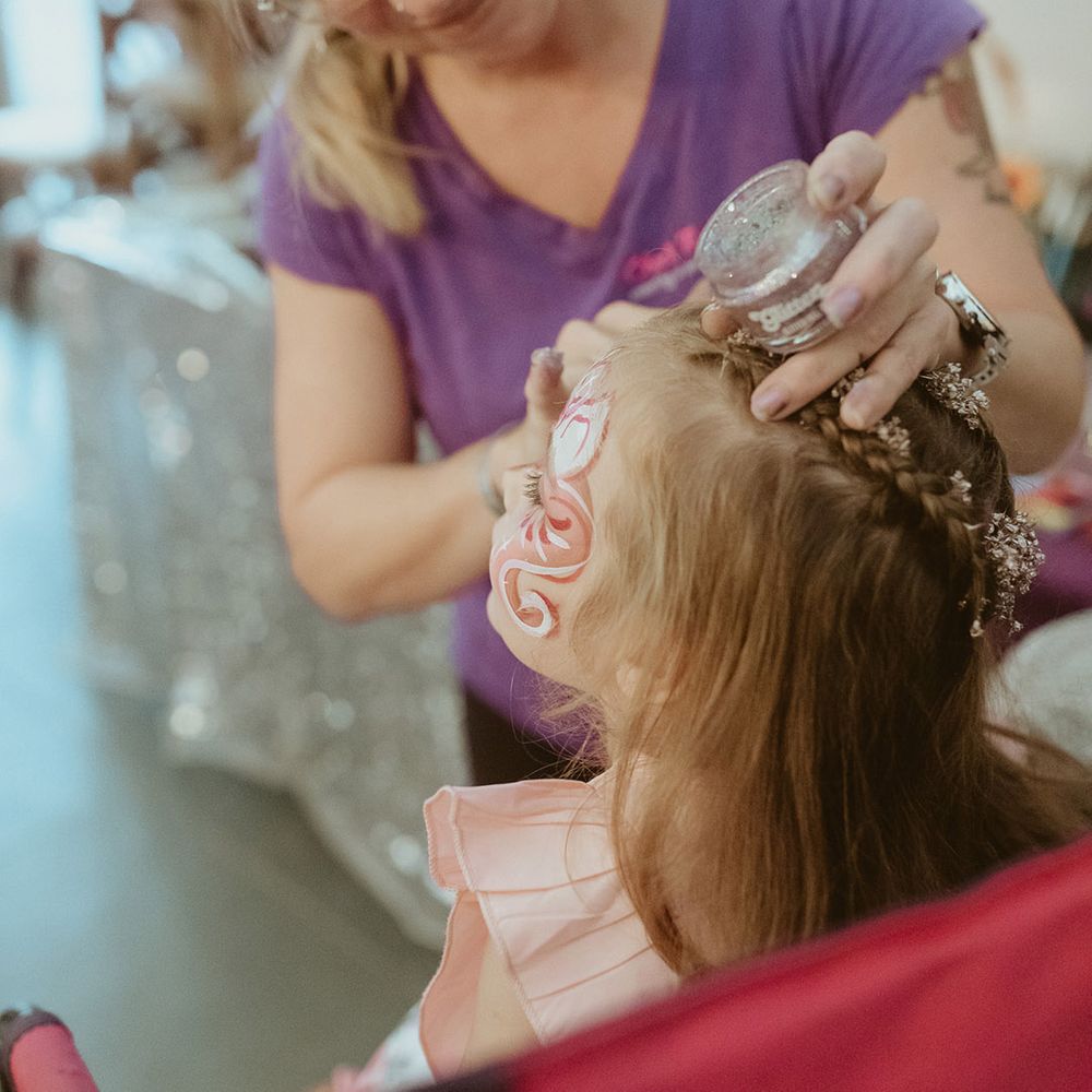 Young girl gets her face painted for the kids entertainment at the bouncy castle wedding in autumn 