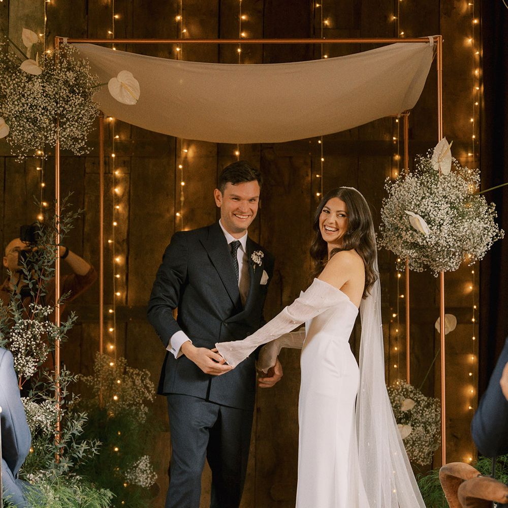 The bride and groom standing at the altar for their bespoke interfaith blessing ceremony with Jewish traditions with gypsophila and anthuriums 