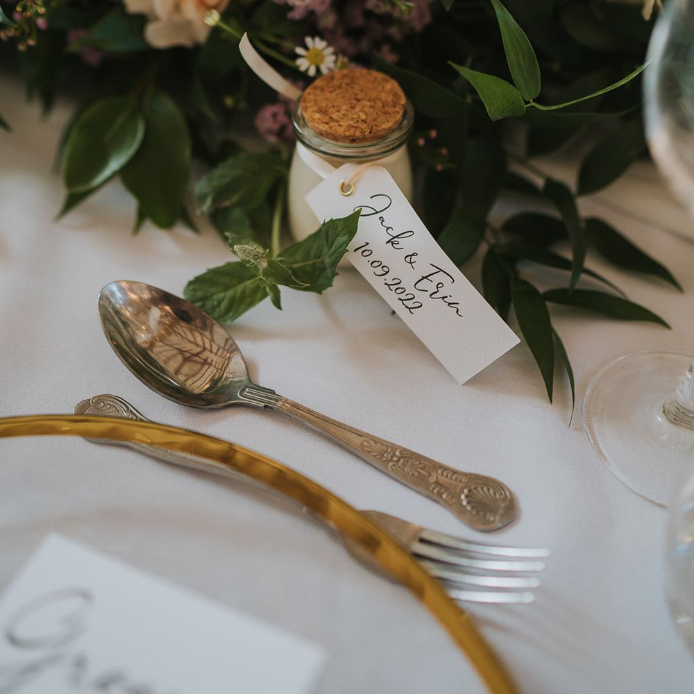 Pink, purple, and white wedding flowers decorating the table with mini wedding favours with personalised label 
