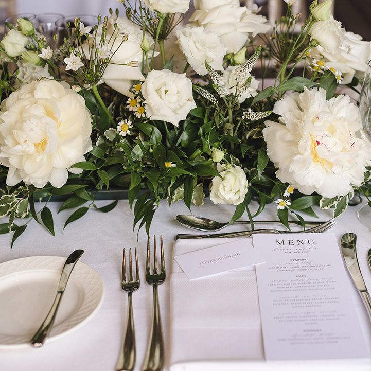 Classic and traditional black and white wedding menu and place setting with white flower arrangement decoration 