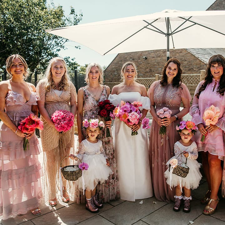 Bridesmaids in pink mismatched bridesmaid dresses holding pink wedding bouquets at tipi wedding 
