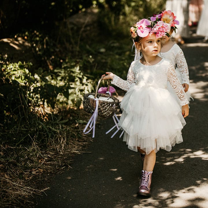 Flower girls in tulle white dresses with colourful flower crown in metallic purple boots 