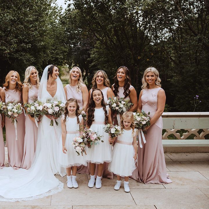 Bridal party wearing blush pink bridesmaid dresses with flower girls in white dresses 