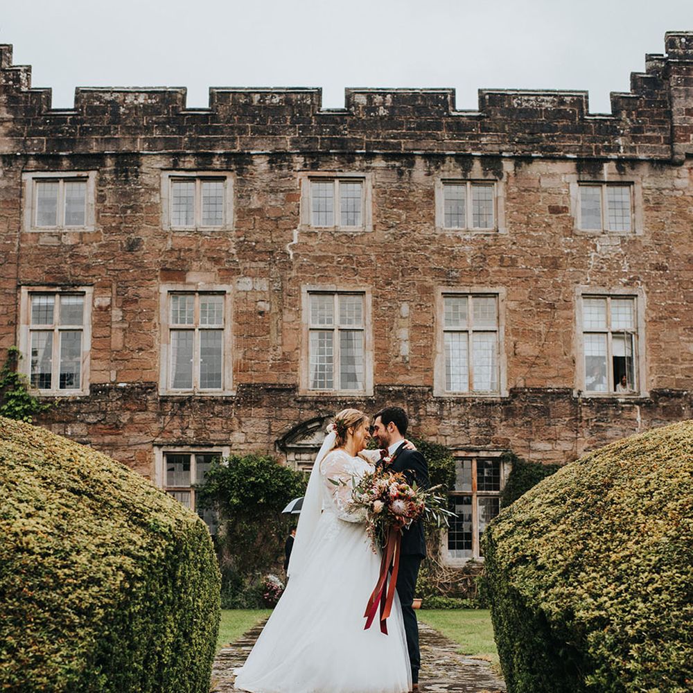 Classic country house wedding venue in the Lake District with the bride and groom sharing a kiss outside the venue 
