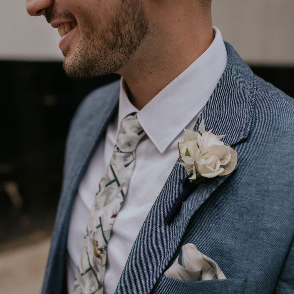 Groom in Blue suit and floral tie with white buttonhole 