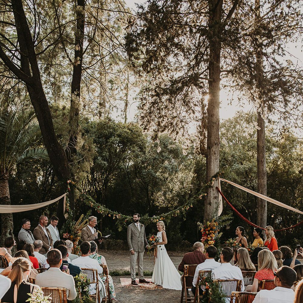 Forest wedding ceremony with wooden chairs and floral aisle flowers 