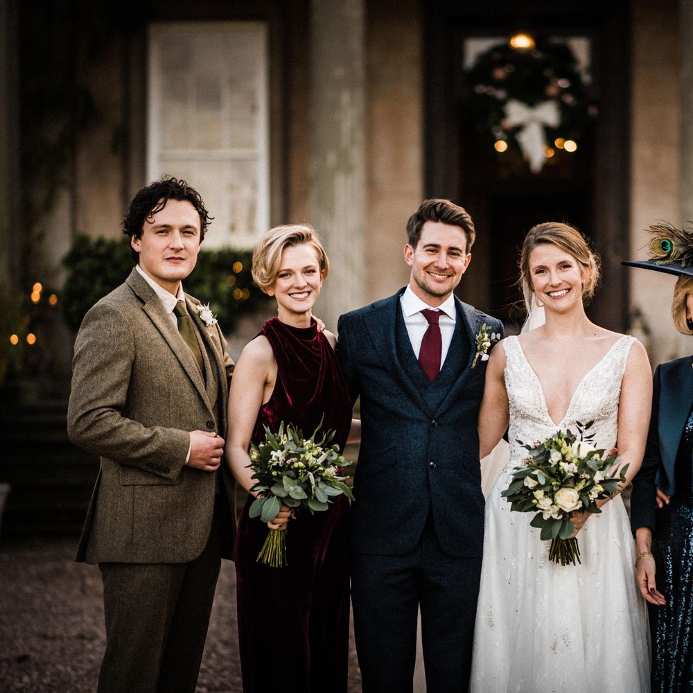 Bride & groom stand with wedding guests outdoors