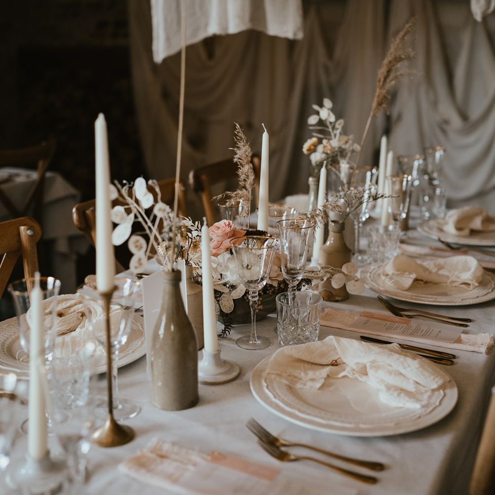 Neutral wedding table decor at modern luxury wedding reception with gold rimmed glasses, ornate tableware, and dried flower centrepiece flowers 
