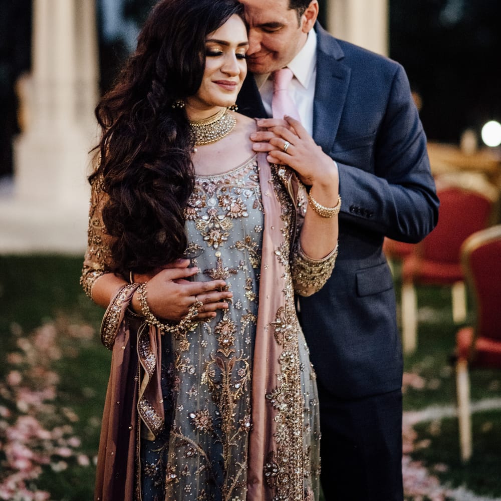 Groom leans into bride as she looks down and wears her dark hair in loose curls