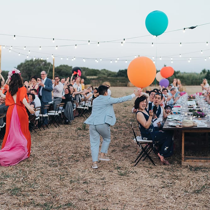 Brides walk together through wedding reception outdoors on their wedding day