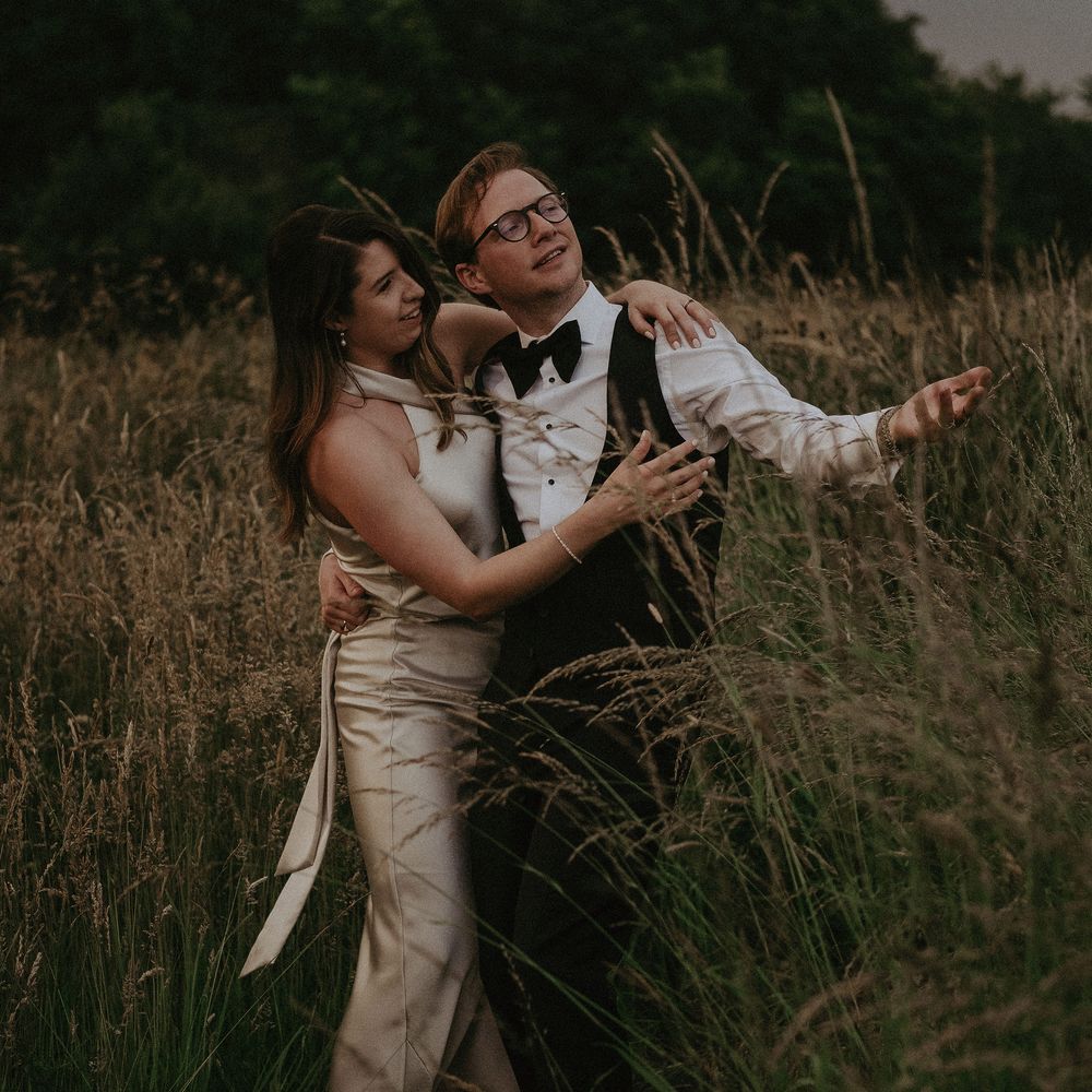 Bride & groom stand together on their wedding day outdoors in the countryside 