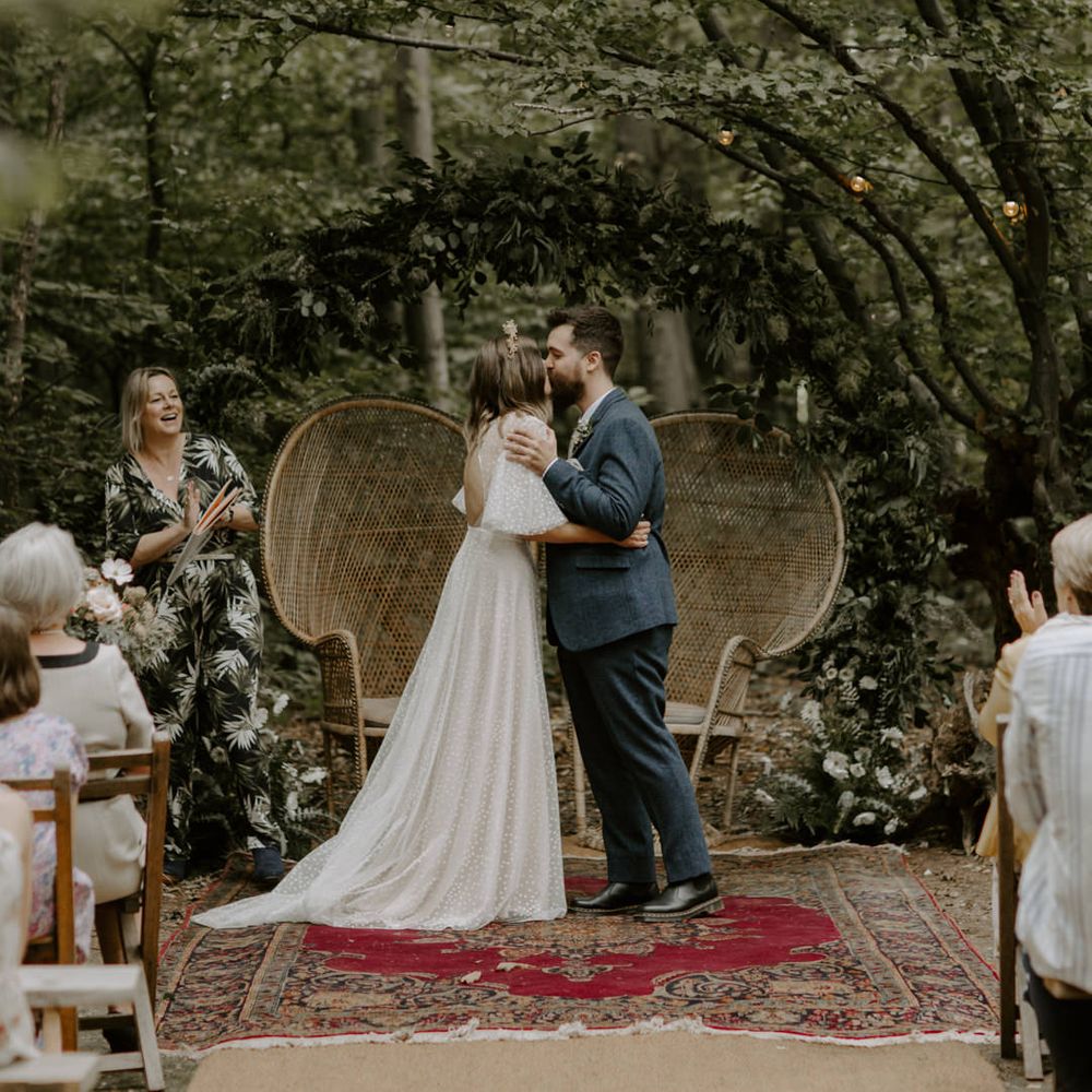 Bride & groom kiss at The Dreys in front of floral archway