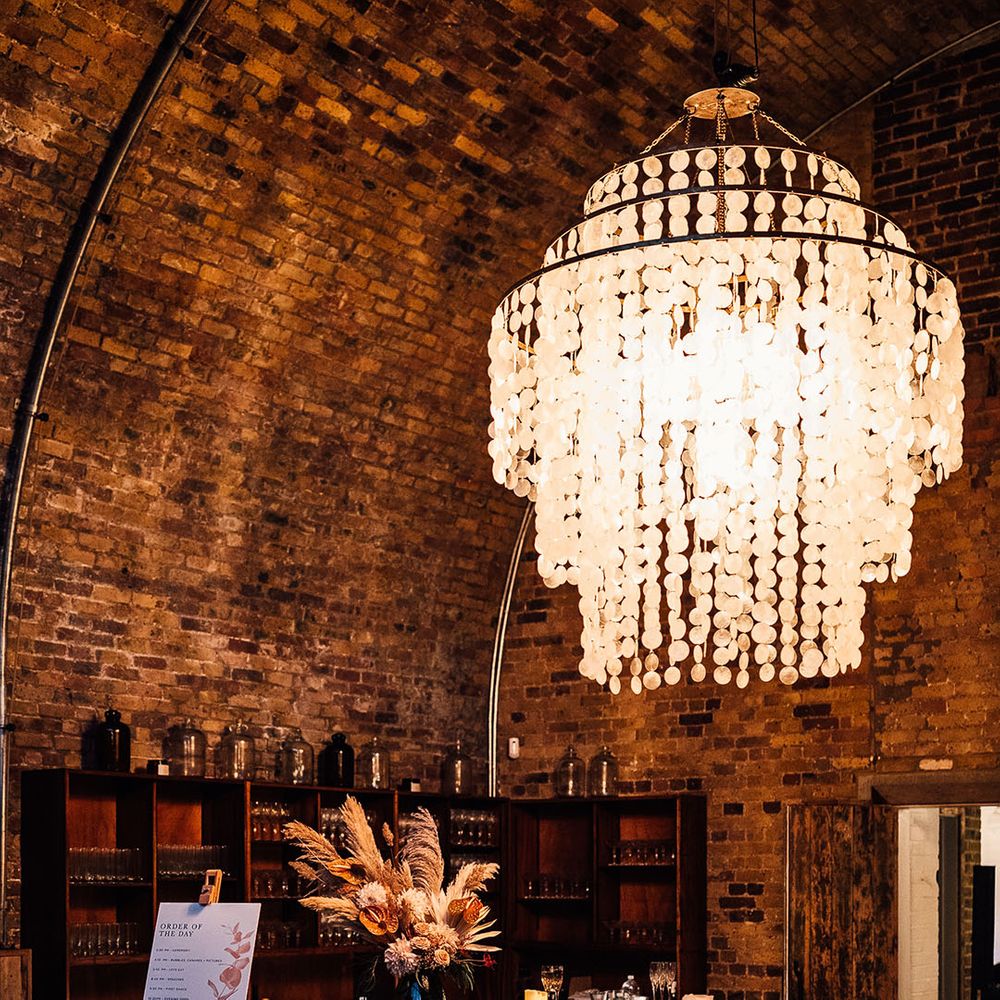 Bar area at 100 Barrington with chandelier, fabric drinks menu, order of the day sign and dried pampas grass and anthurium flowers in a vase 
