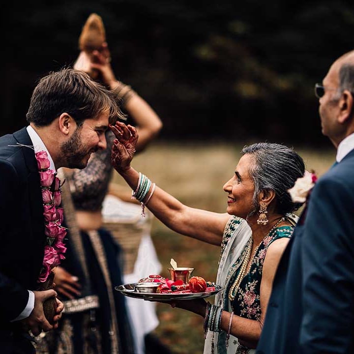 Mother of bride smiles as she welcomes groom at Indian wedding